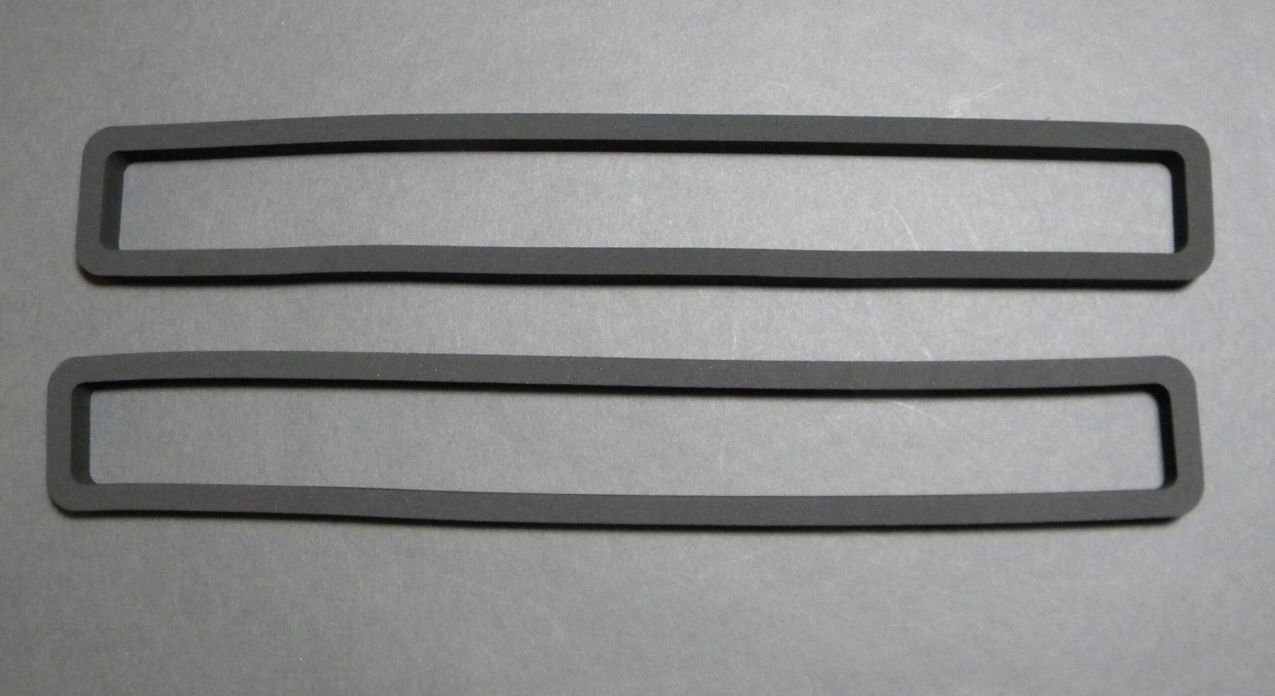 Two rubber rectangular gaskets on gray background